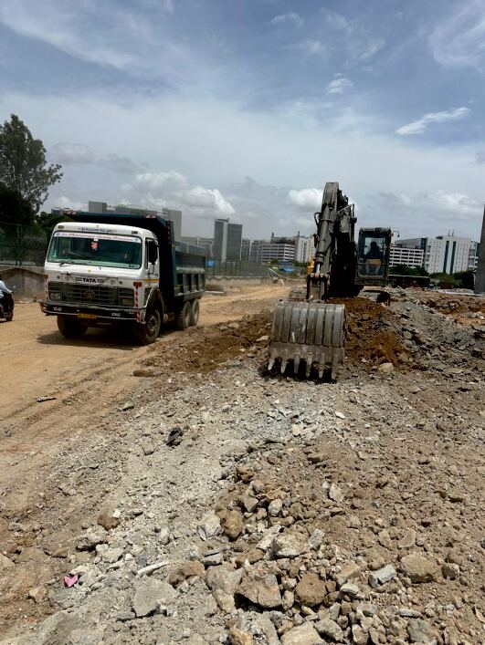 Excavator loading a dump truck during mass excavation works on a Bengaluru road site